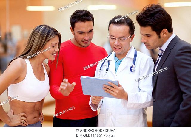 Hispanic people and doctor using tablet computer in gym