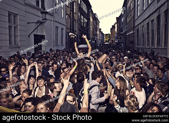 A young woman is crowd surfing at the annual street og block party Distortion Festival in Copenhagen. All streets are packed with happy party people