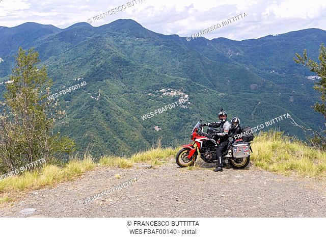 Italy, Tuscany, Pistoia, father and son having a break at viewpoint during a motorbike trip