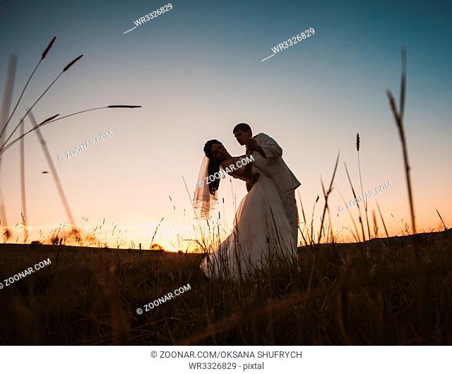 Wedding couple dancing in mountain hill on sunset