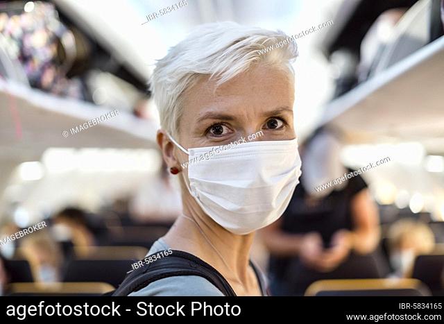 Woman standing in the airplane wearing face mask, Portugal, Europe
