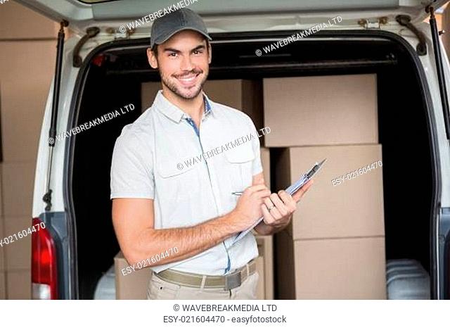 Delivery driver smiling at camera beside his van