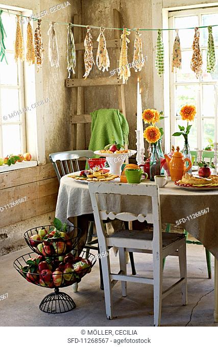 A table laid with apple chips, apple pastries, a vase of flowers and tea crockery