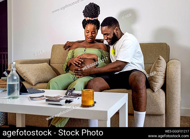 Pregnant woman sitting on sofa with boyfriend at home