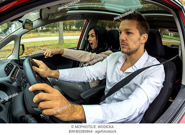 young man driving car with gesticulating young woman as co-driver, Austria