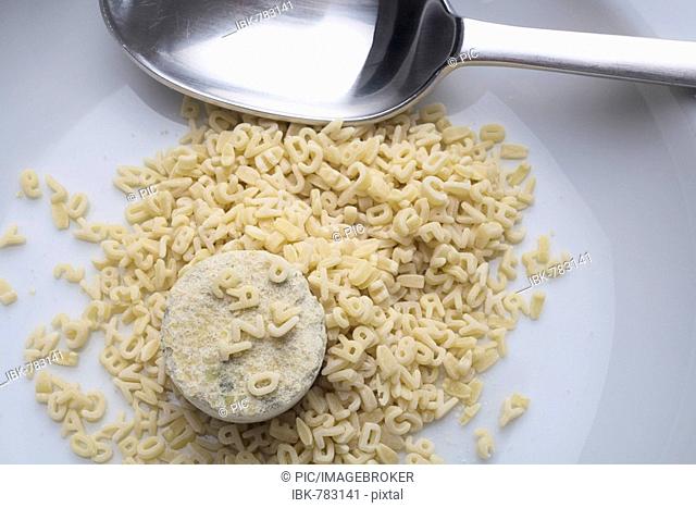 Lump of dry instant soup on a plate surrounded by alphabet noodles