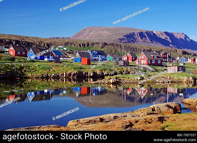 Wooden houses reflected in the water, mountains in the background, Qeqertarsuaq, Disko Island, Artkis, Greenland, Denmark, North America
