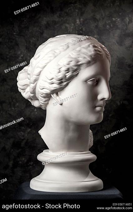 White gypsum copy of ancient statue of Venus de Milo head for artists on a dark textured background. Plaster sculpture of woman face