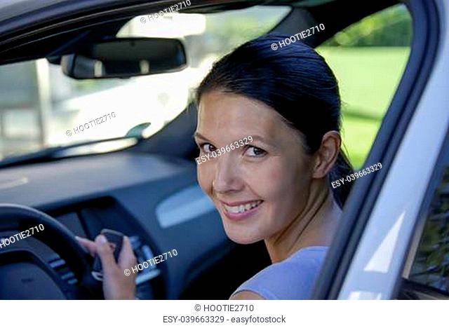 woman holding sitting in her car and smiling to camera