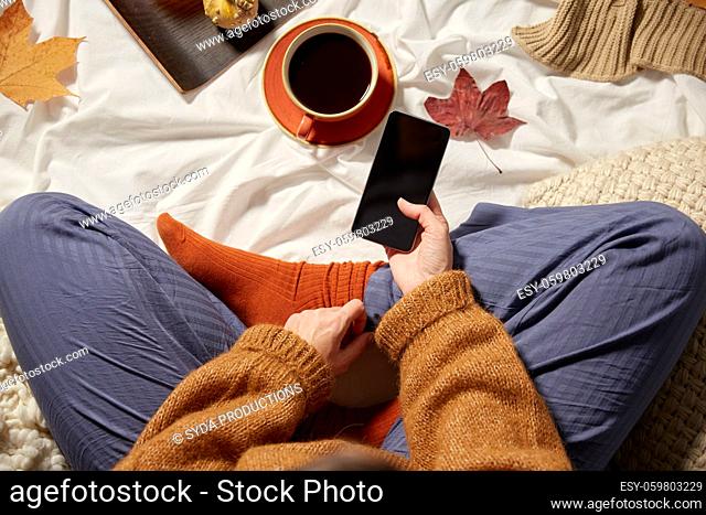 woman with smartphone at home in autumn