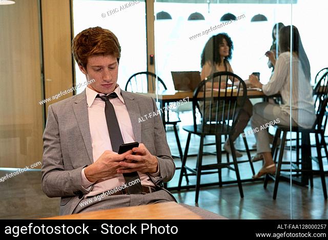 Young businessman using smart phone in office