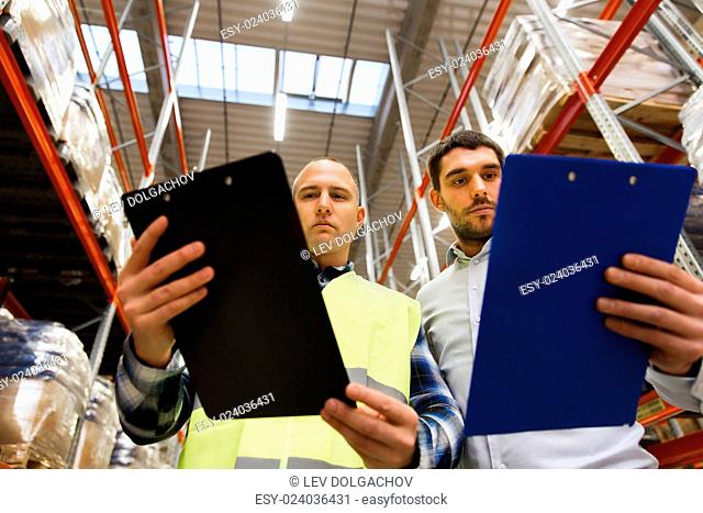 wholesale, logistic, people and export concept - manual worker and businessmen with clipboards at warehouse