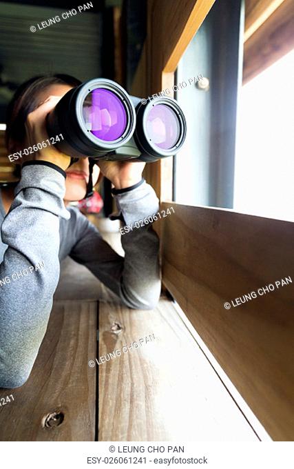 Young woman use of the binocular at wooden house
