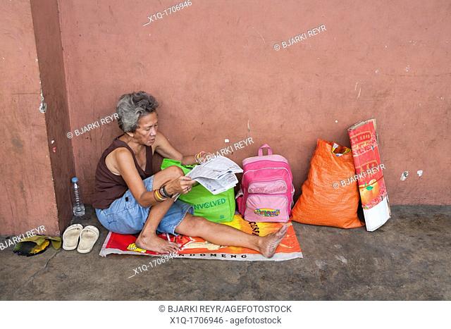 A Filipino woman reading the newspaper on the sidewalk  Cebu City, Cebu, Visayas, Philippines