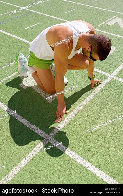 Athlete in start position getting ready for running on sports track