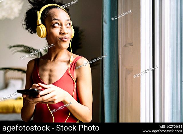 Thoughtful young woman looking away while listening music at home