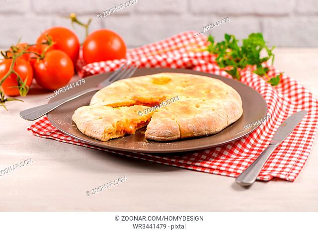Italian food, pizza calzone with tomato, spinach and cheese on wooden background