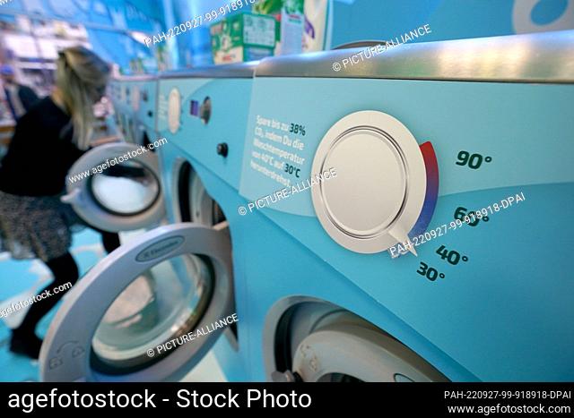 27 September 2022, Hamburgo;: A woman fills a washing machine at a public laundry in Hamburg...From next Friday to Sunday