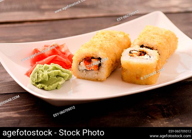 Japanese seafood sushi, roll on a white plate on wooden table