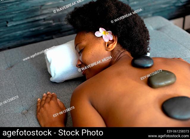 African american woman woman with eyes closed receiving hot stone massage at home
