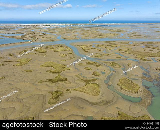 Network of channels and streams at low tide. In the marshland of the Bahía de Cádiz. In the background the village of Sancti Petri and the coastline of the...