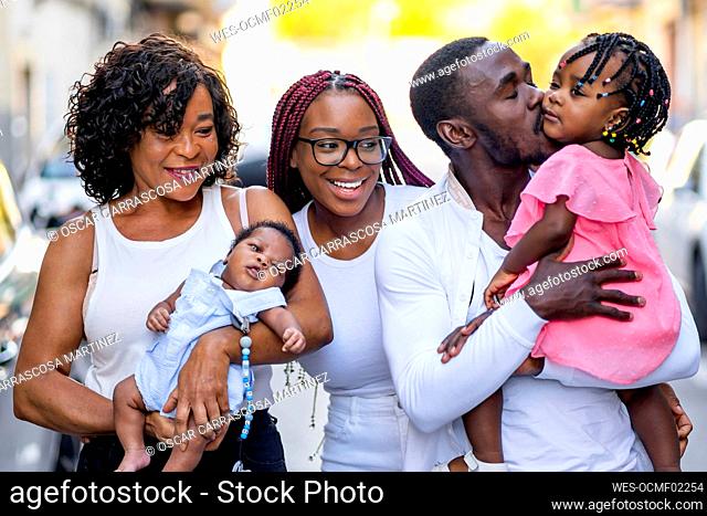 Young man kissing daughter by family