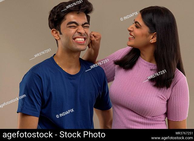 A YOUNG WOMAN HAPPILY TEASING YOUNGER BROTHER