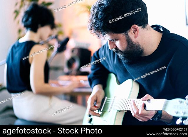 Male composer playing guitar in studio
