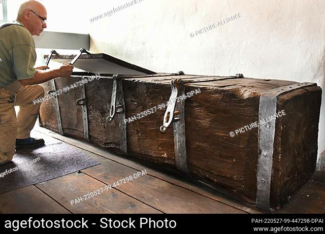 17 May 2022, Saxony-Anhalt, Wölkau: In the village church in Wölkau, near Bad Dürrenberg, retired master painter Gerald Hartmann looks at an old wooden chest...