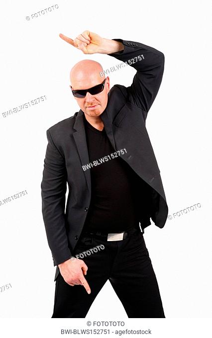 bald headed man with sunglasses pointing with his index finger to the side