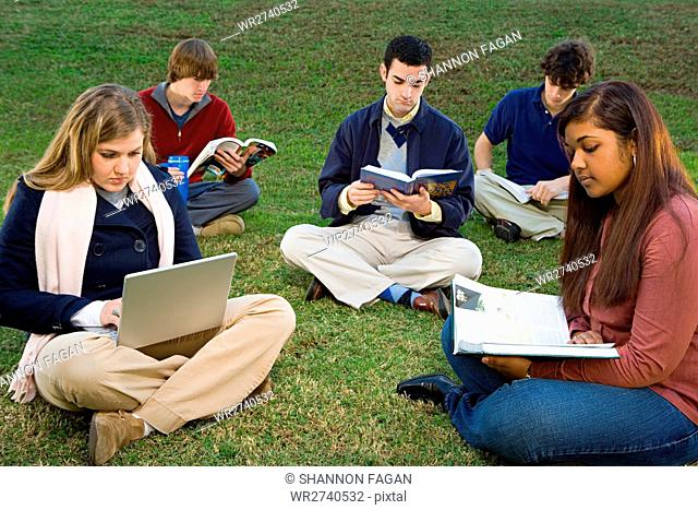 Five students sat reading outdoors