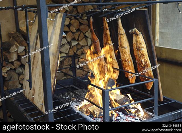 Smoked fish via wood log fire at German Christmas market at Benrath Castle near Dusseldorf