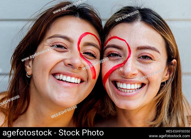 Cheerful women with heart drawn on face