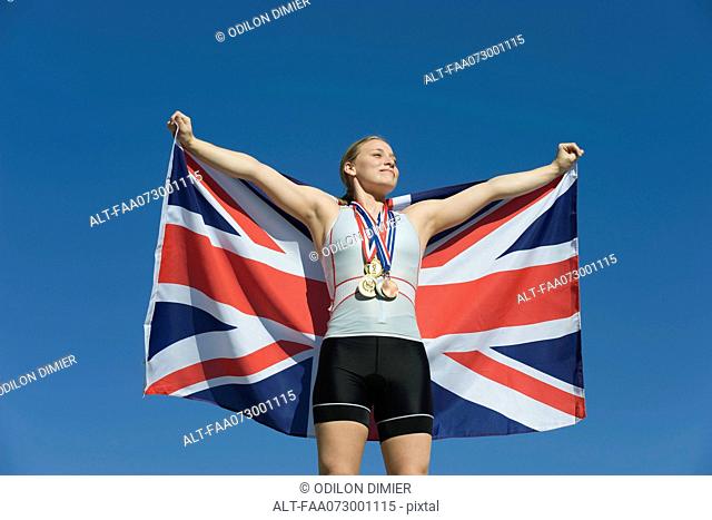 Female athlete being honored on podium, holding up British flag