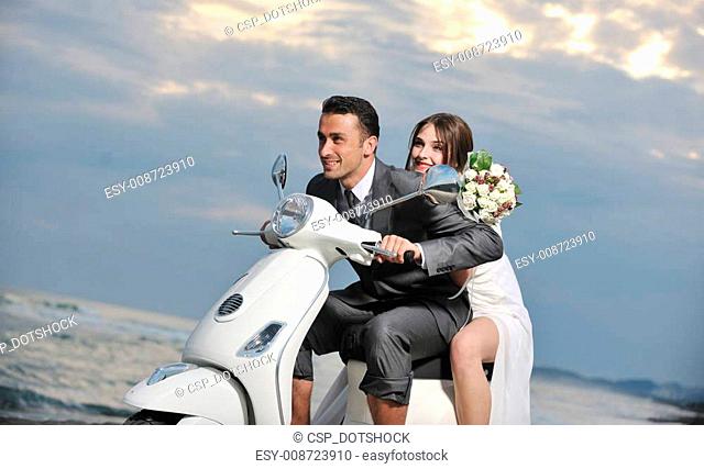 just married couple on the beach ride white scooter