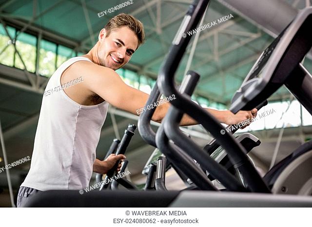 Portrait of happy man exercising on the elliptical machine