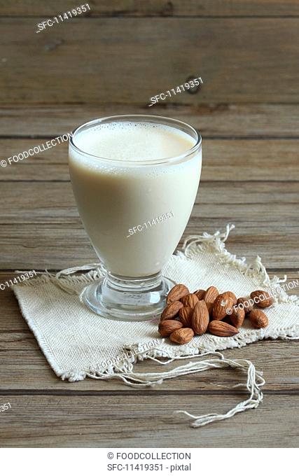 A glass of almond milk with almonds next to it