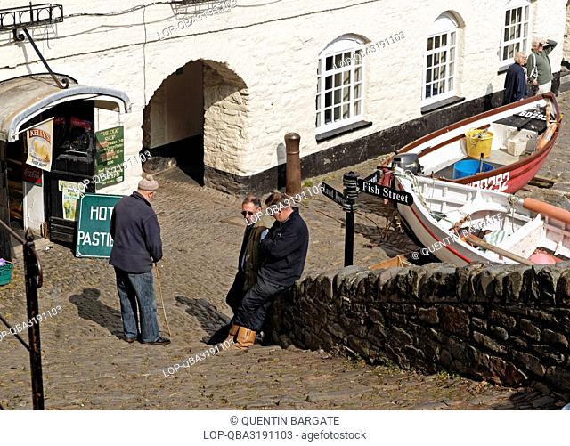 England, Devon, Clovelly. Locals in conversation at the foot of steps in the famous, historic, fishing village of Clovelly in North Devon