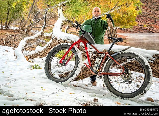 senior male cyclist with a mountain fat bike on a lake shore in fall scenery, Horsetooth Reservoir in foothills of northern Colorado