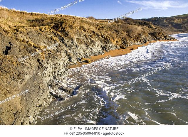 Surf eroding Kimmeridge clay low cliffs at high tide, Ringstead Bay, Dorset, England, January