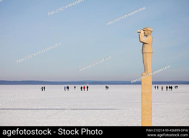 14 February 2021, Lower Saxony, Steinhude: People are out and about on the frozen Steinhuder Meer in the sunshine - in the foreground the sculpture ""The...