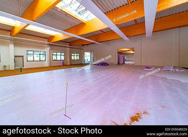 Inside a large factory building, purple insulation panels are laid on the floor