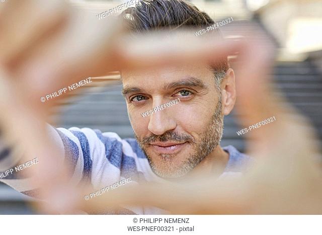 Portrait of mature man building frame with his fingers