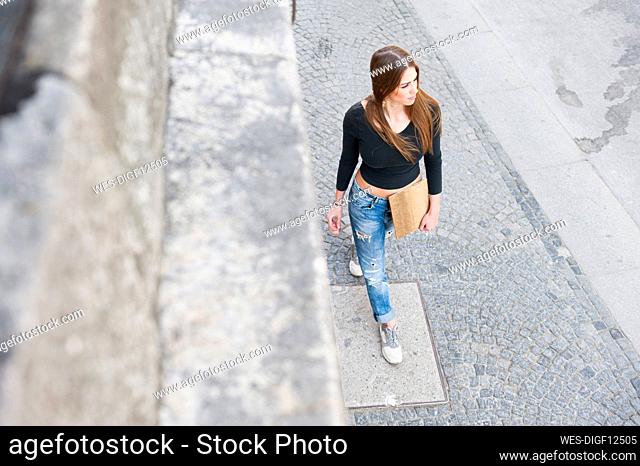 Fashionable woman walking on sidewalk in city