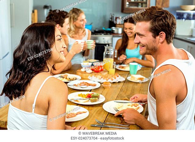 Smiling couple looking at each other while having breakfast