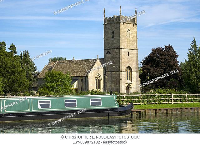 Late spring sunshine on colourful narrowboats moored near St Marys Church on the Gloucester & Sharpness Canal at Frampton on Severn, Gloucestershire, UK