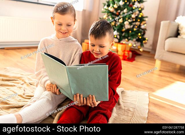 happy children reading book on christmas at home