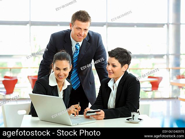 Young businesspeople having a business meeting at coffee table in office lobby, using laptop computer