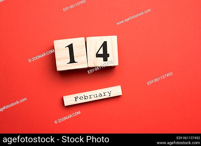 wooden calendar with date 14 february on a red background, holiday valentine's day, flat lay