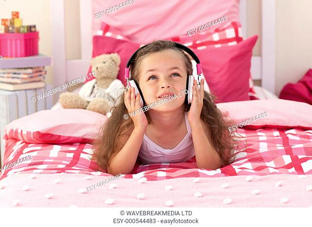 Cute little girl listening music in the bedroom